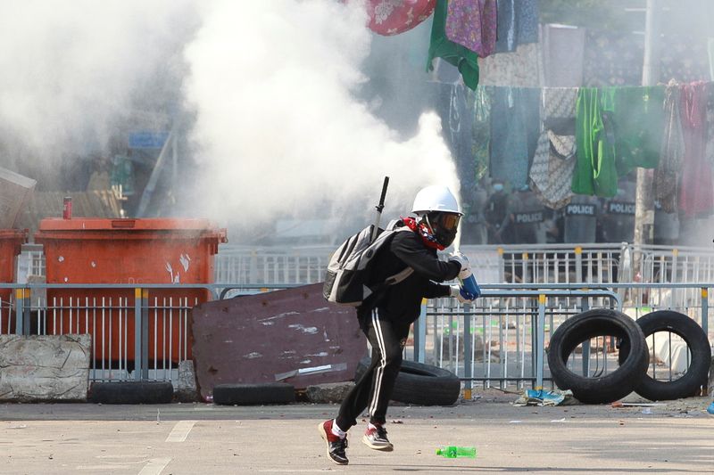 An anti-coup demonstrator sprays a fire extinguisher as he runs