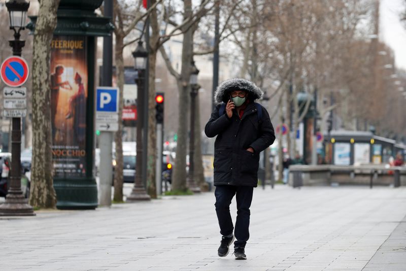 FILE PHOTO: A man wearing a protective face mask walks