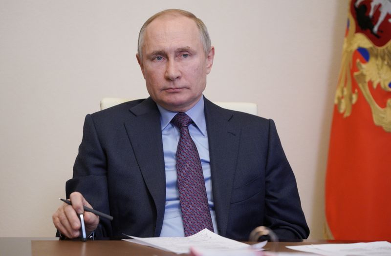 Russian President Vladimir Putin attends a video conference call outside