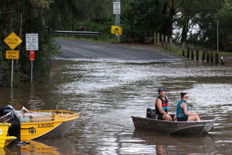 People in a boat navigate floodwaters resulting from prolonged rains