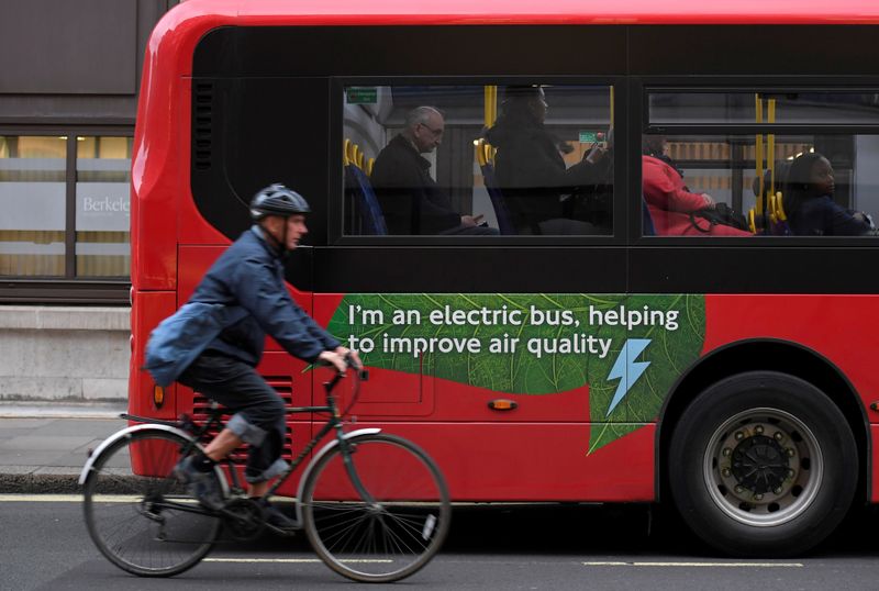 FILE PHOTO: A cyclist rides past an electric public bus