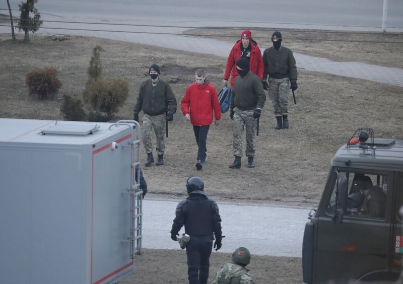 Belarusian law enforcement officers lead men away in a street