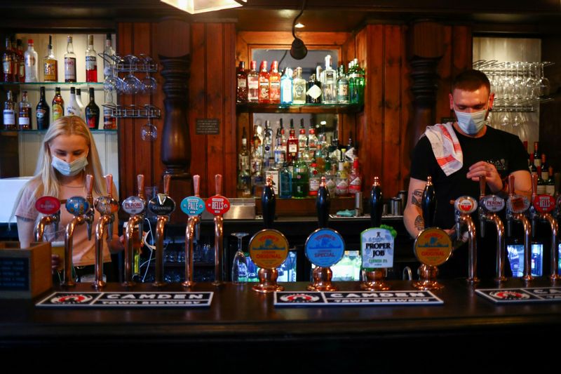 FILE PHOTO: Bartenders pour drinks in a pub in London
