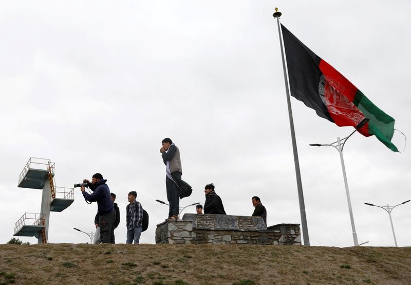 FILE PHOTO: Youths take pictures next to Afghan flag in