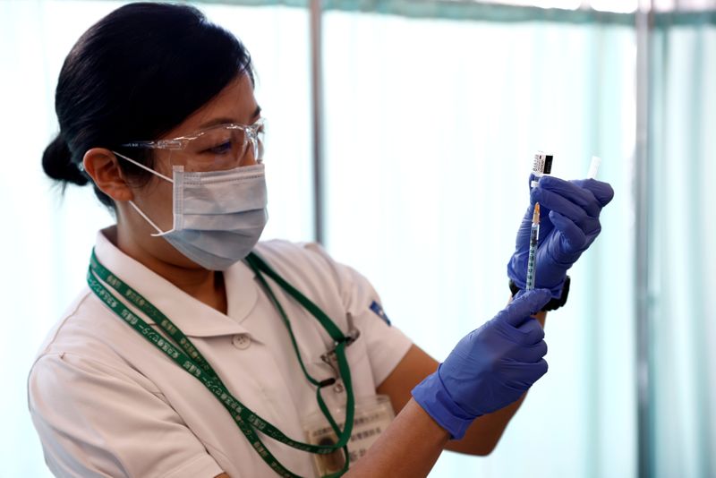 A medical worker fills a syringe with a dose of