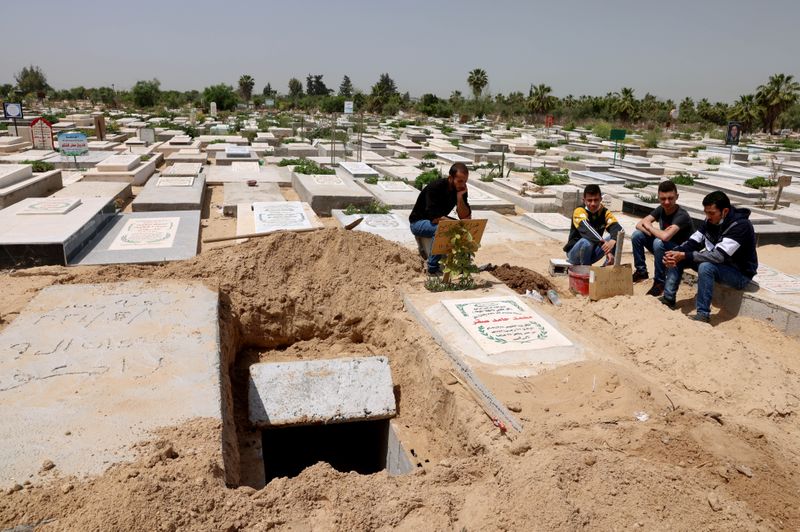 Palestinians wait to bury the body of their relative, who