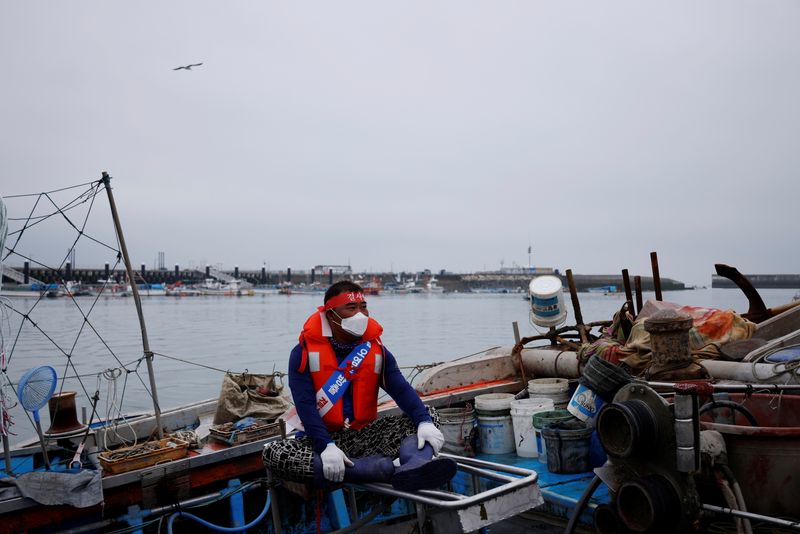 A South Korean fisherman sits on his boat during a