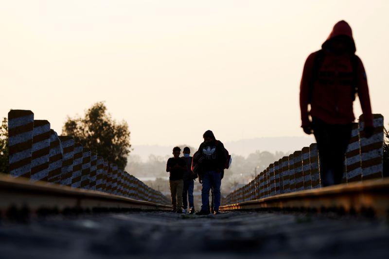 Central American migrants walk on the train track near the