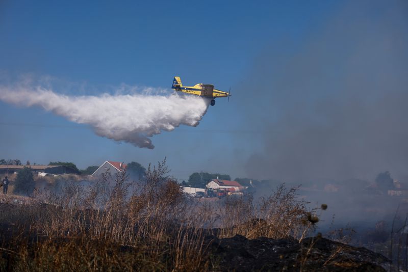 An Israeli firefighting plane extinguishes a fire on a field
