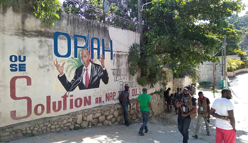 People walk past a wall with a mural depicting Haiti’s