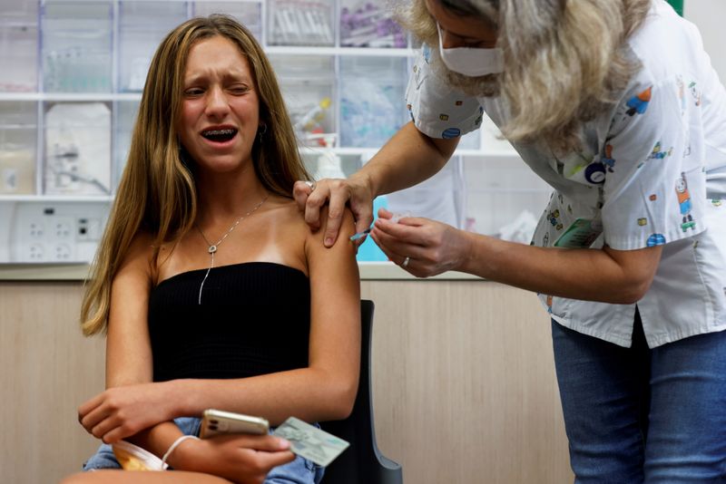FILE PHOTO: A teenager reacts while receiving a dose of