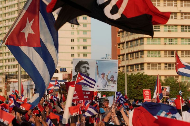 People carry a poster with photographs of Fidel Castro, Miguel
