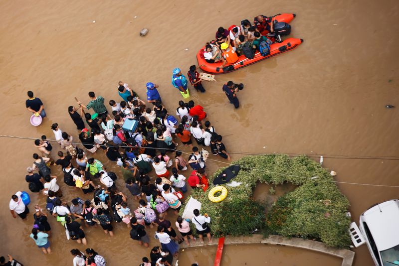 People standing on a flooded road wait to be evacuated