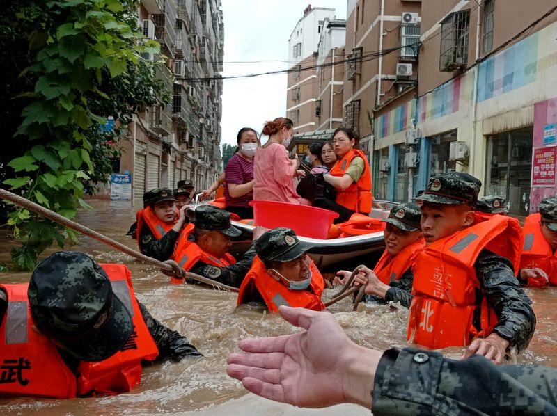 Paramilitary police officers evacuate residents stranded by floodwaters with a