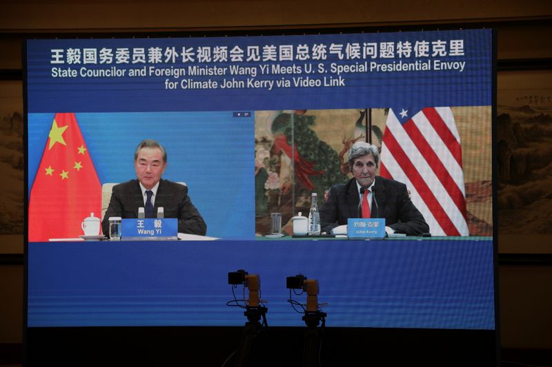 John Kerry is seen on a screen with Wang Yi