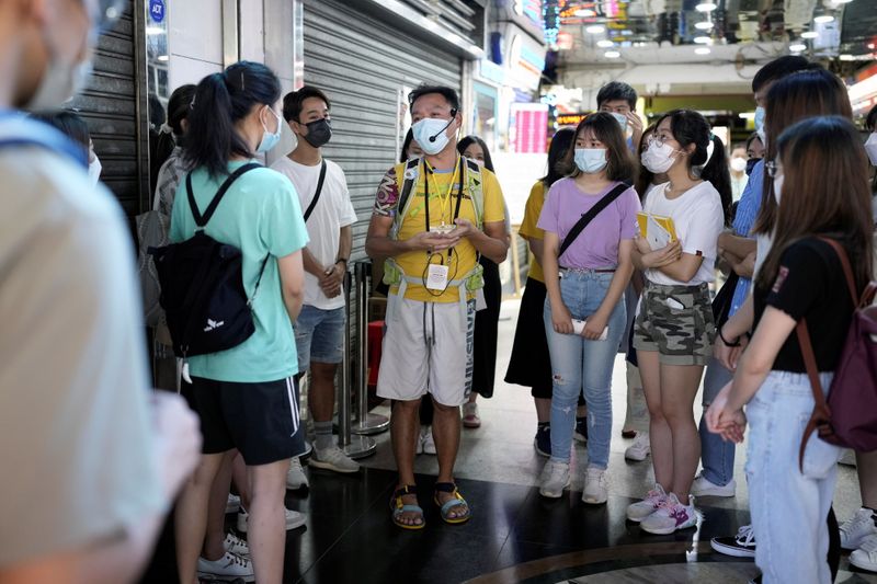 Tour guide Michael Tsang speaks to tourists during a tour