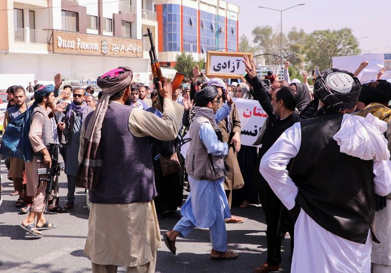 Taliban forces try to stop the protesters, as they shout