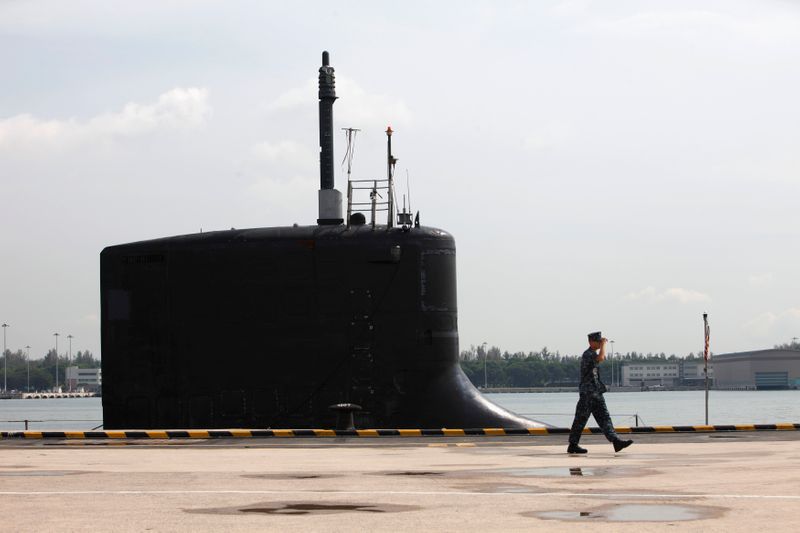 U.S. Navy personel walks past USS North Carolina submarine docked