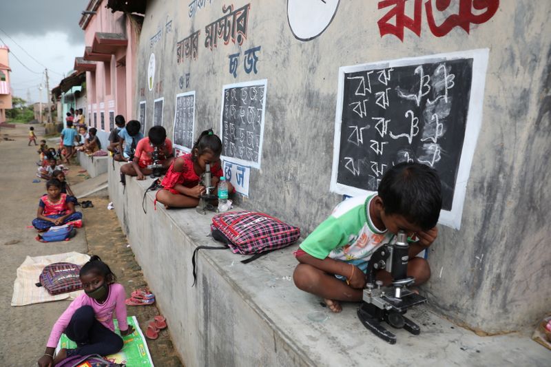 Children use microscopes as they attend an open-air class outside