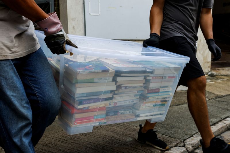A mover collects a box of books after police search