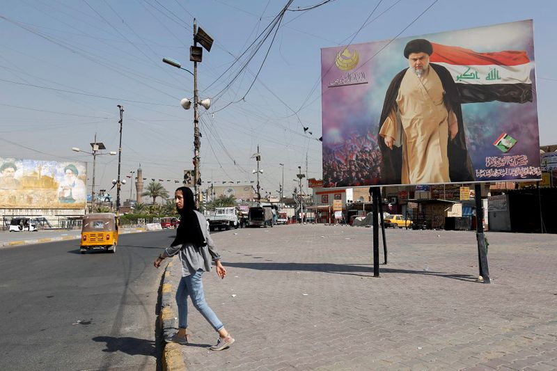 Girl walks near a poster of Iraqi Shi’ite cleric Moqtada