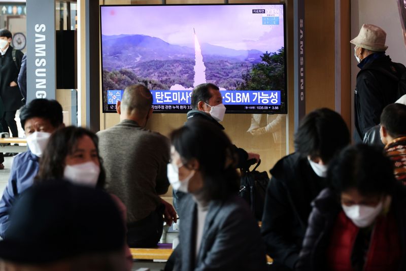 People watch a TV broadcasting file footage of a news