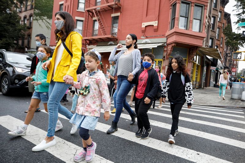 Parents walk with children to school, amid the coronavirus disease
