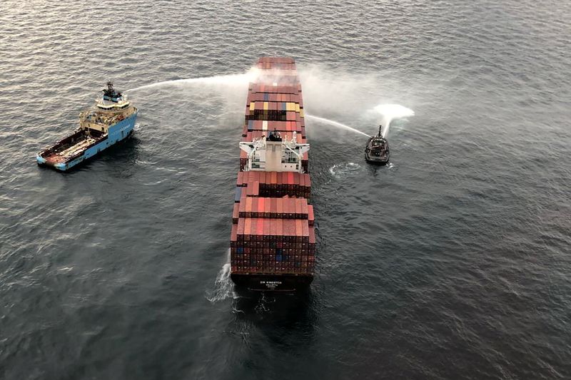 Tugboats pour water on the container ship Zim Kingston after