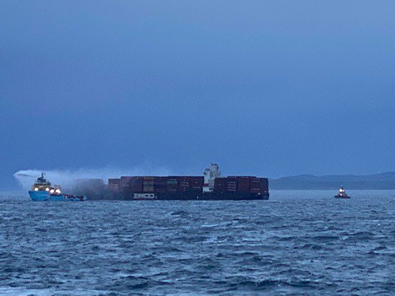 Tugboat pours water on the container ship Zim Kingston after