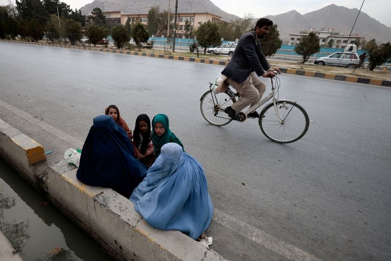 FILE PHOTO: Women wearing burqas sit with their children as