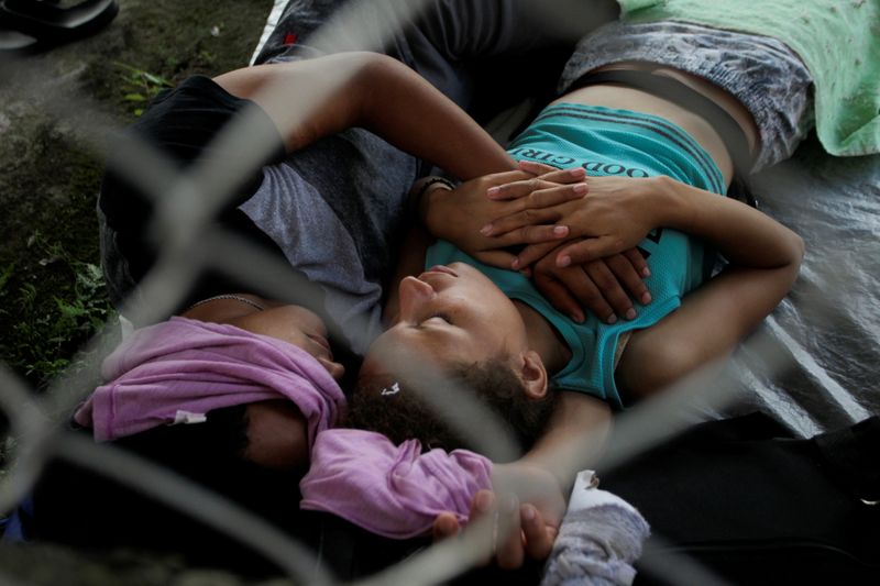 Migrants rest before they continue walking in a caravan heading