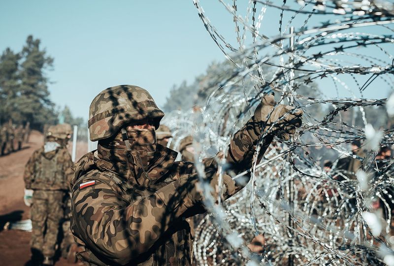 A Polish soldier instals barbed wire on the Poland/Belarus border
