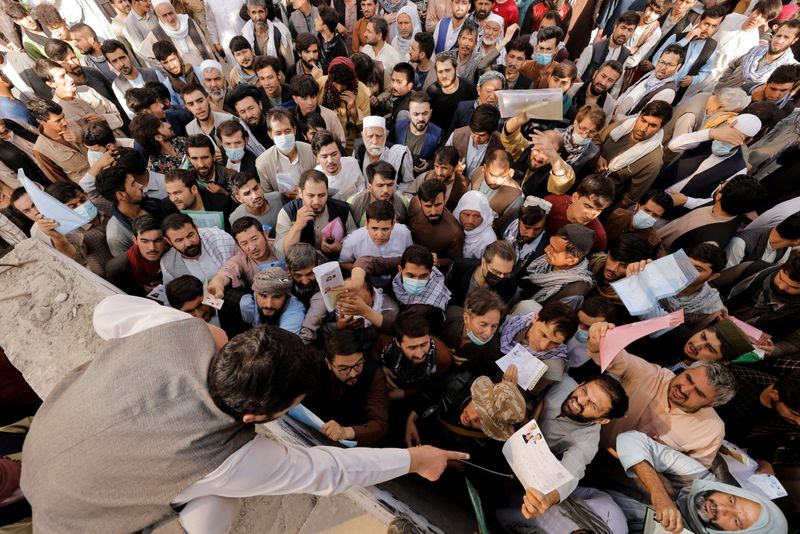 Afghans gather outside the passport office after Taliban officials announced