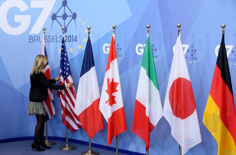 An official adjusts flags during the G7 summit at the