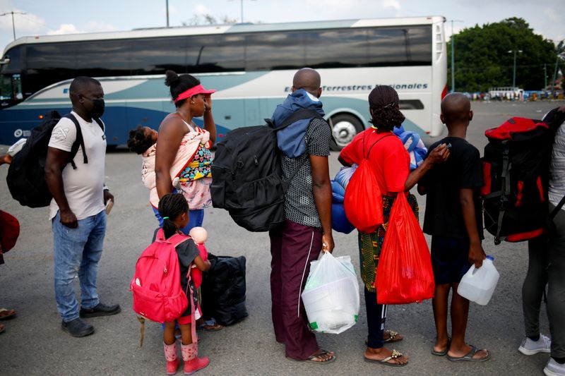 Migrants queue to get on buses after accepting an offer