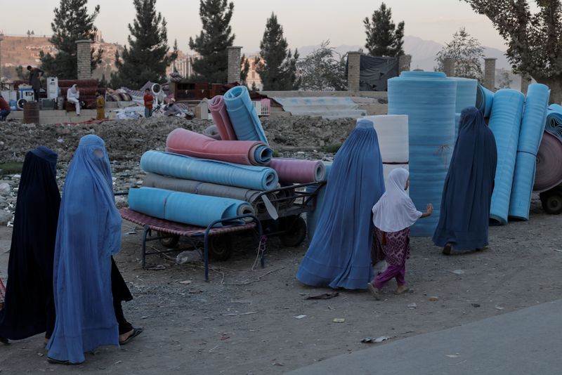 Women wearing burqas walk in a second-hand market where people