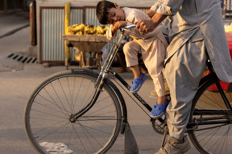 FILE PHOTO: A boy sleeps as he rides a bicycle