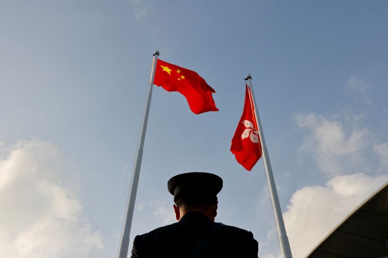 A police officer stands guard below China and Hong Kong