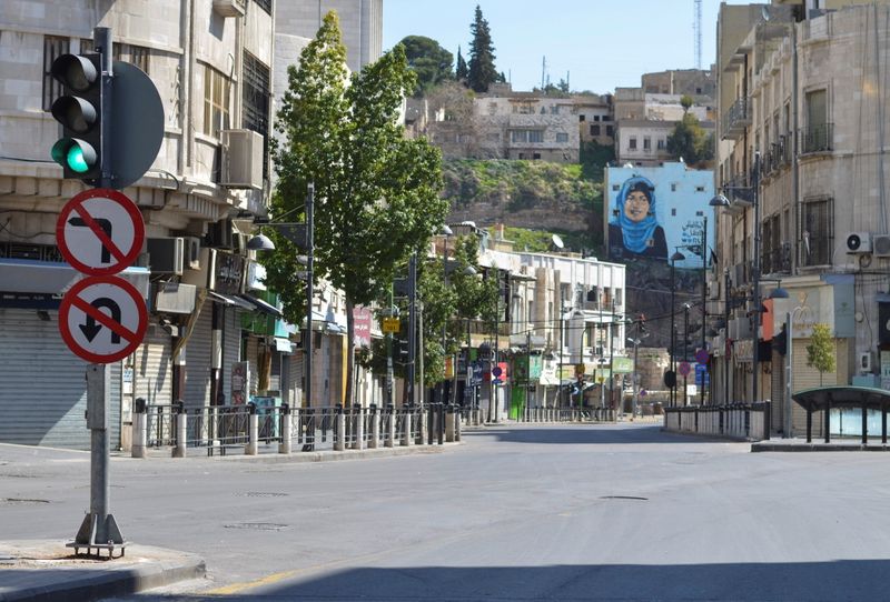 View shows closed shops along an empty street in Amman