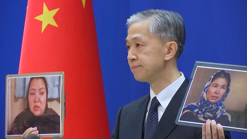 Chinese Foreign Ministry spokesman Wang Wenbin holds pictures while speaking