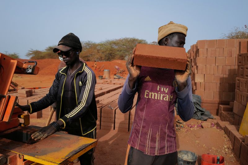 A worker carries a newly made brick at the Elementerre