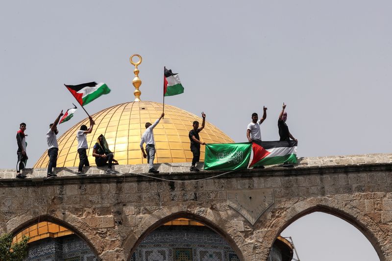 Palestinians hold flags as they stand at the compound that
