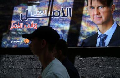 A man walks past a banner depicting Syria’s President Bashar