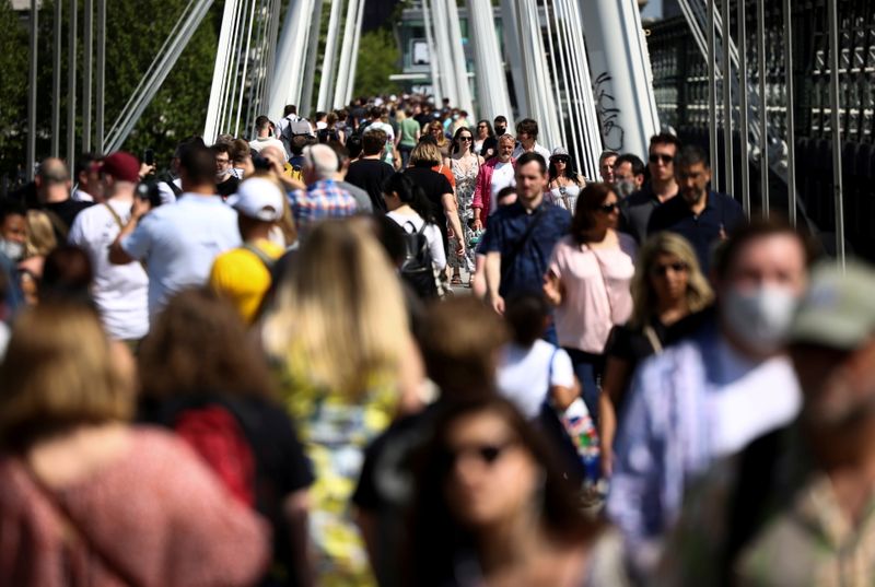 FILE PHOTO: People walk across Millennium Bridge during sunny weather,