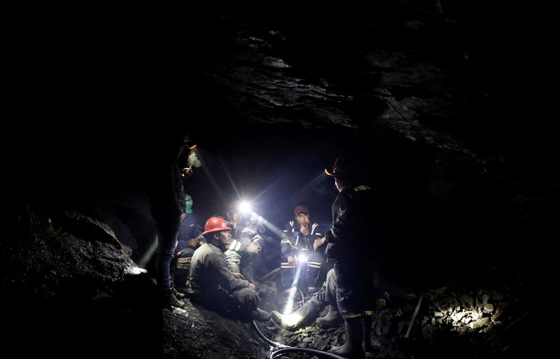 FILE PHOTO: Miners talk to each other as they sit