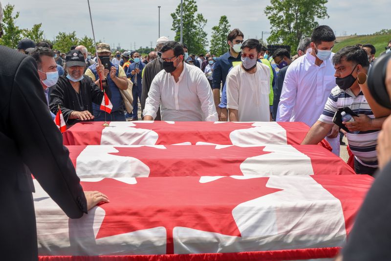 FILE PHOTO: People transport three flag-wrapped coffins at the funeral