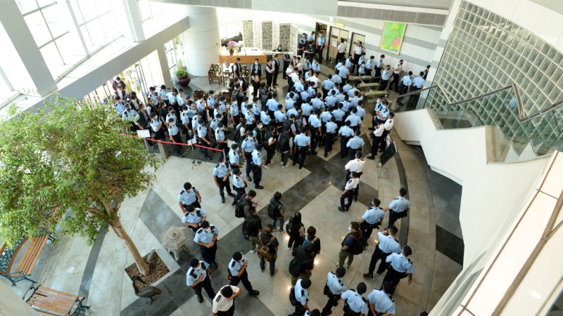 Police officers gather at the headquarters of Apple Daily in