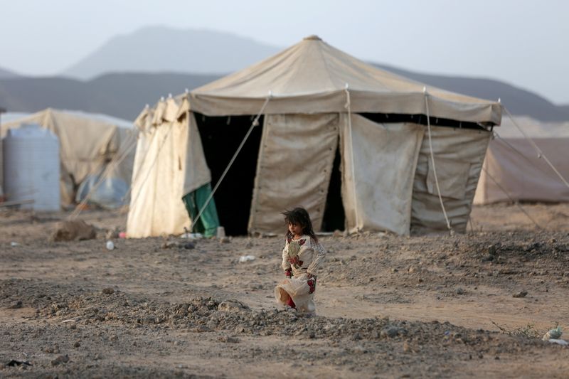 FILE PHOTO: Girl walks past a tent at a camp