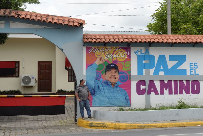 A man stands next to a photo of Nicaraguan President
