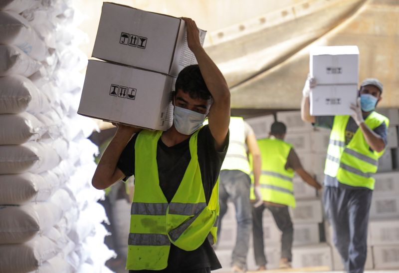 Workers carry boxes of humanitarian aid near Bab al-Hawa crossing